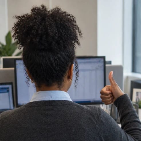 Woman giving a thumbs up at her office desk